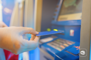 Mão insere cartão em caixa eletrônico para receber benefício do INSS via Pix.